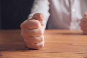 man clenches fist in an anger management therapy session