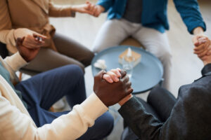 people clasp hands while learning about group therapy benefits